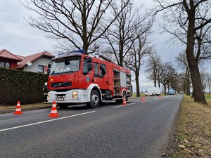 Na zdjęciu widoczny wóz straży pożarnej, w tle widoczne miejsce wypadku, radiowozy, policjanci.