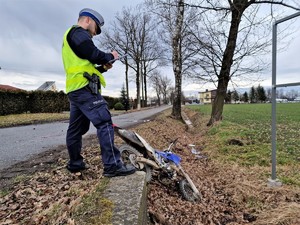 Na zdjęciu policjant podczas czynności na miejscu zdarzenia, w rowie widoczny motocykl.