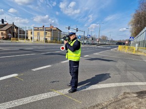 Zdjęcie przedstawia policjanta ruchu drogowego podczas pomiaru prędkości.