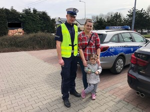 Zdjęcie przedstawia umundurowanego policjanta ruchu drogowego wraz z kobietą i dzieckiem.