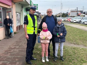 Zdjęcie przedstawia umundurowanego policjanta ruchu drogowego z mężczyzną i dwójką dzieci.