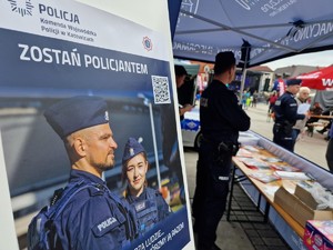 Zdjęcie przedstawia: plakat dotyczący naboru do służby w policji. Z tyłu widoczni policjanci.