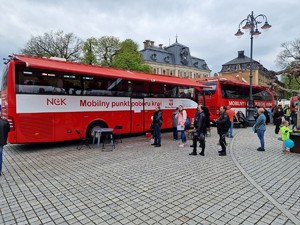 Zdjęcie przedstawia: ludzi stojących w kolejkach przed dwoma krwiobusami.