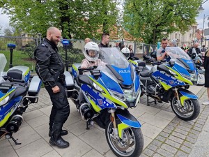 Zdjęcie przedstawia: dorosłych i dzieci obok policyjnych motocykli. Obok widoczni policjanci, którzy pokazują policyjny sprzęt.