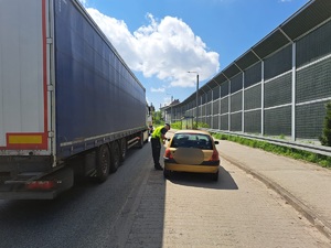 Zdjęcie przedstawia umundurowanego policjanta podczas kontroli drogowej.