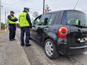 Zdjęcie przedstawia: umundurowanego policjanta i funkcjonariusza SOK stojących przy samochodzie osobowym.