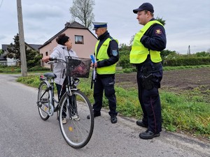 Zdjęcie przedstawia: mundurowych podczas rozmowy ze starszą kobietą, która trzyma rower.