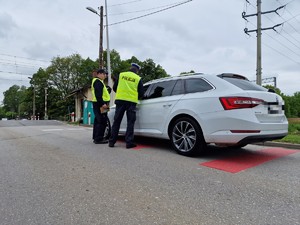 Zdjęcie przedstawia: mundurowych prze samochodzie, z tyłu przejazd kolejowy.