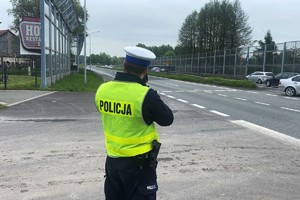 Zdjęcie przedstawia policjanta podczas pomiaru prędkości pojazdów.