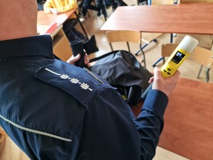 Zdjęcie przedstawia urządzenie do badania stanu trzeźwości, które trzyma w ręce umundurowany policjant.