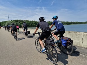 Zdjęcie przedstawia: rowerzystów podczas przejazdu obok zbiornika wodnego.