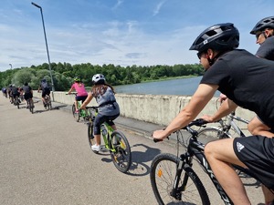 Zdjęcie przedstawia: rowerzystów podczas przejazdu obok zbiornika wodnego.