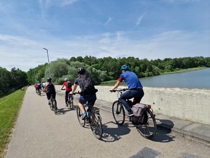 Zdjęcie przedstawia: rowerzystów podczas przejazdu obok zbiornika wodnego.