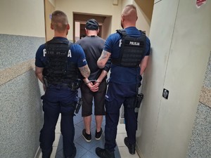 Zdjęcie przedstawia dwóch umundurowanych policjantów z zatrzymanym mężczyzną.