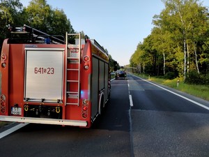 Zdjęcie przedstawia: wóz straży pożarnej, z tyłu widoczny helikopter ratunkowy.