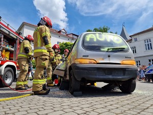 Zdjęcie przedstawia: strażaków podczas rozcinania drzwi