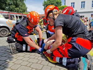 Zdjęcie przedstawia: ratowników medycznych którzy przedstawiają jak udziela się pomocy osobie poszkodowanej