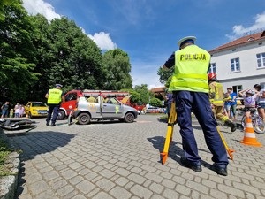 Zdjęcie przedstawia: trzech umundurowanych policjantów prowadzący czynność podczas oględzin wypadku