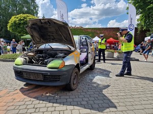 Zdjęcie przedstawia: policjanta który robi zdjęcie samochodu po wypadku