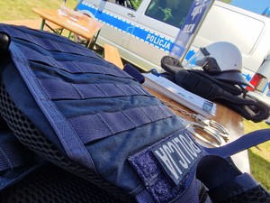 Zdjęcie przedstawia: policyjne wyposażenie. Z tyłu widoczny radiowóz.