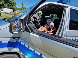 Zdjęcie przedstawia: dwoje dzieci w policyjnym radiowozie.