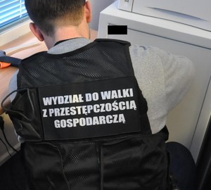 Zdjęcie przedstawia: policjanta w kamizelce z napisem Przestępczość gospodarcza.