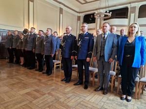 Zdjęcie przedstawia: zebranych gości i policjantów stojących &amp;quot;na baczność&amp;quot; i śpiewających hymn.