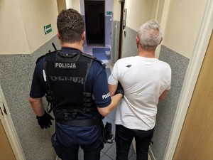 Zdjęcie przedstawia umundurowanego policjanta wraz z zatrzymanym mężczyzną.