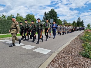 Zdjęcie przedstawia: maszerujących jezdnią ludzi.