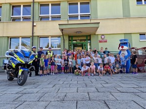 Zdjęcie przedstawia grupę dzieci, policjantów i motocykl policyjny.