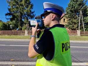 Zdjęcie przedstawia: policjanta podczas pomiaru prędkości.