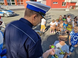 Zdjęcie przedstawia: policjanta, który daje dziecku odblask.