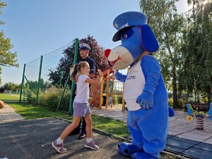 Zdjęcie przedstawia: dziecko, które przybija piątkę policyjnej maskotce.