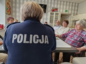 Zdjęcie przedstawia : policjantkę tyłem, dalej widoczni seniorzy.