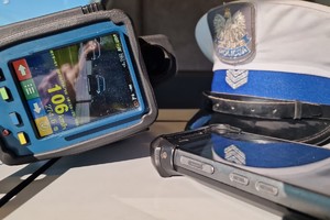 Zdjęcie przedstawia miernik prędkości wraz z pomiarem, czapkę policjanta wydziału ruchu drogowego oraz urządzenie do sprawdzania osób i rzeczy.