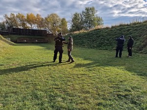 Zdjęcie przedstawia: policjantów podczas ćwiczeń na strzelnicy. Obok umundurowanych policjantów widoczni instruktorzy.