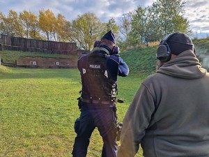 Zdjęcie przedstawia: instruktora, który stoi za policjantem podczas ćwiczenia.