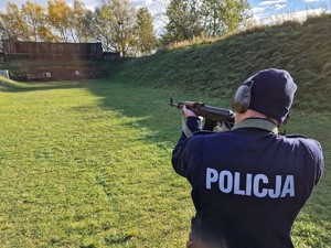 Zdjęcie przedstawia: policjanta z karabinkiem AK na strzelnicy.