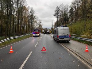 Zdjęcie przedstawia: zablokowaną drogę. Widoczny wóz straży pożarnej i policyjny radiowóz.