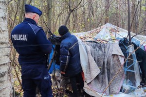 Zdjęcie przedstawia: umundurowanego policjanta podczas rozmowy z osobą bezdomną.