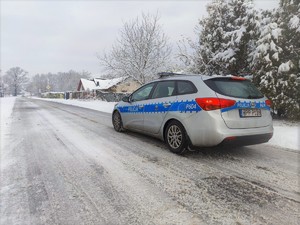 Zdjęcie przedstawia policyjny oznakowany radiowóz policyjny na zaśnieżonej jezdni.