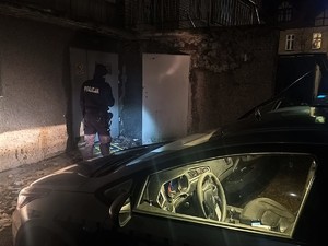 Zdjęcie przedstawia: umundurowanego policjanta, który wchodzi do opuszczonego budynku.