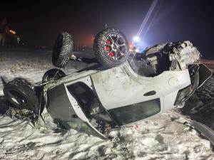 Zdjęcie. Uszkodzony samochód osobowy, leży na dachu.
