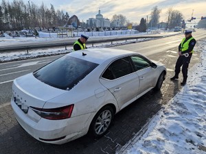 Zdjęcie przedstawia: dwóch umundurowanych policjantów podczas kontroli drogowej.