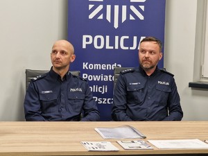 Zdjęcie przedstawia dwóch policjantów siedzących za biurkiem.