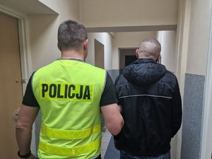 Zdjęcie przedstawia policjanta z zatrzymanym mężczyzną.