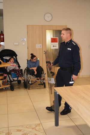 Zdjęcie. Policjant pokazuje uczestnikom tarcze.