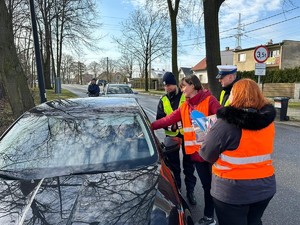 Zdjęcie przedstawia: dwoje mundurowych podczas działań profilaktycznych z kierowcami samochodów.