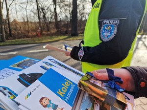 Zdjęcie przedstawia: ulotki edukacyjne dla dzieci, z tyłu widoczny policjant.