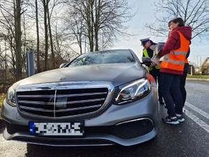 Zdjęcie przedstawia: samochód osobowy. Widoczny mundurowy i dwie kobiety. Wszyscy rozmawiają z osobą wewnątrz pojazdu.